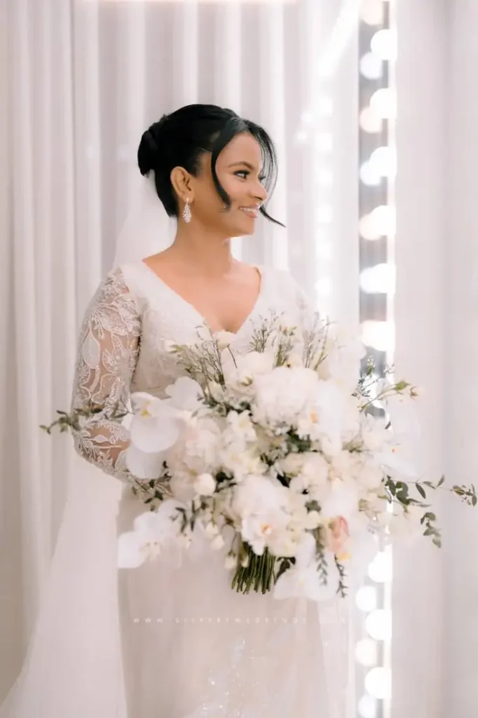 Bride in lace gown holding a white orchid bouquet