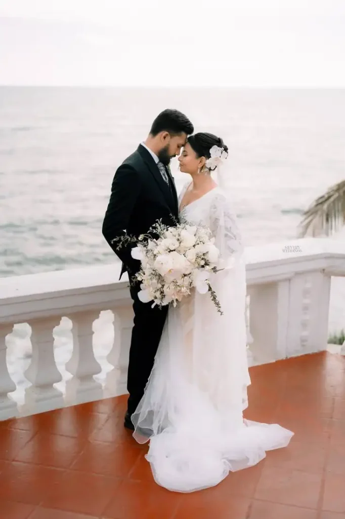 Bride and groom touching foreheads by the sea