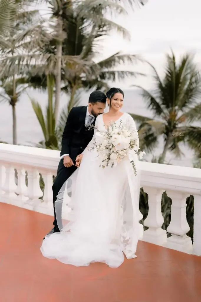 Groom holding the bride from behind among the palms